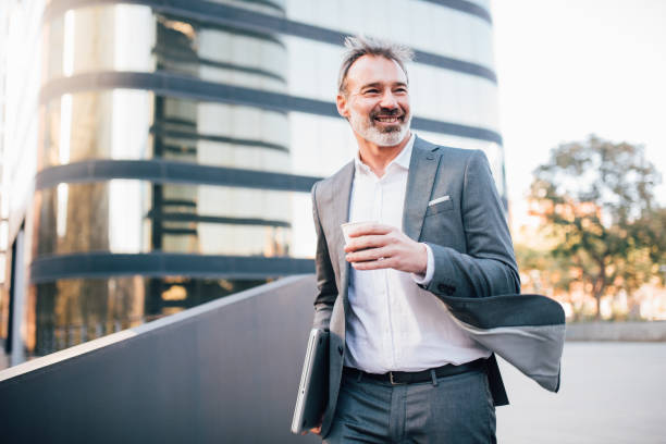 istock Man holding laptop and drinking coffee outdoors 1157549716