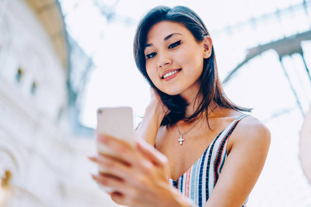 istock Positive young woman reading latest news from social network browsing web page on mobile, attractive asian girl installing application on modern smartphone satisfied with internet connection 1157550074