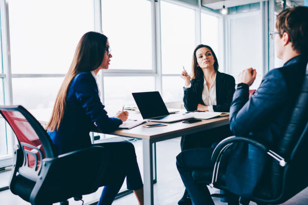 istock Confident male director explaining working process to female colleagues while sitting in front of laptop computer with mock up screen for young internet advertising, concept of business and teamwork 1157554415