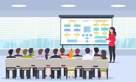 Business person teaches a lecture on business strategy, e-commerce and marketing for a sitting audience and using a blackboard in a classroom with panoramic windows. Business presentation, motivation for a crowd of people.