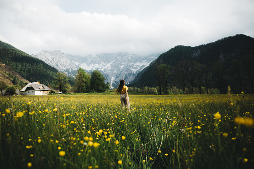Woman walking on the flower meadow with mountain view in Slovenia