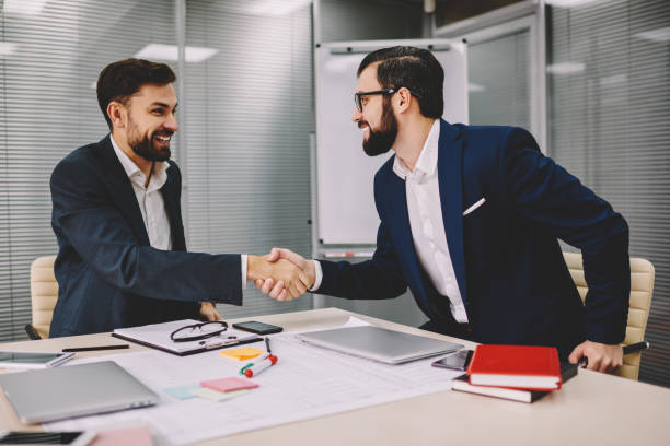 istock Two successful businessmen dressed in formal wear shaking hands gesturing prosperous partnership of finance company during meeting in office.Happy professional traders have deal about cooperation 1157559968