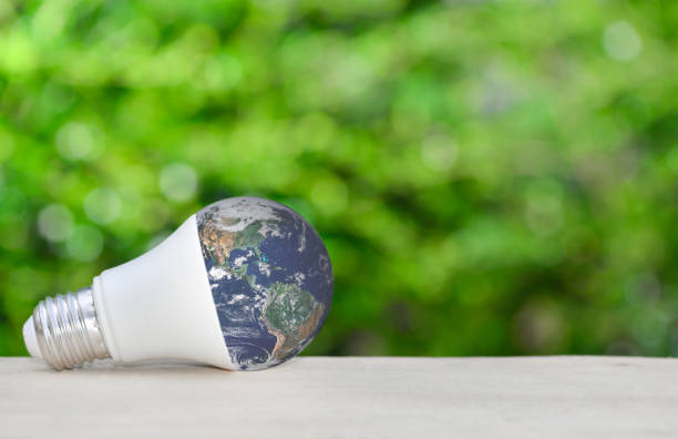 istock LED bulb as a globe on wooden table with green nature background for eco saving concept.Elements of this image furnished by NASA 1157567645