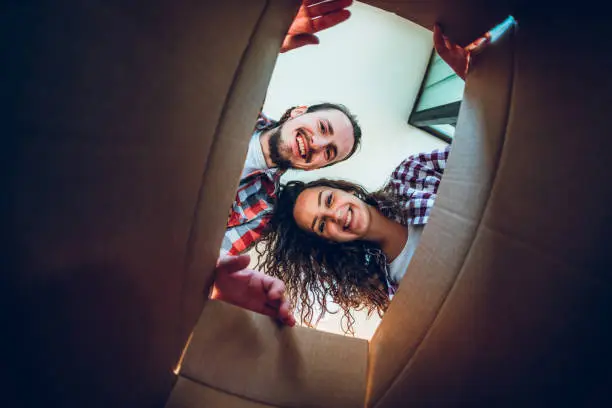 Happy young caucasian couple looking inside the cardboard box.