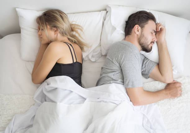 Young couple sleeping back to back in their bed stock photo