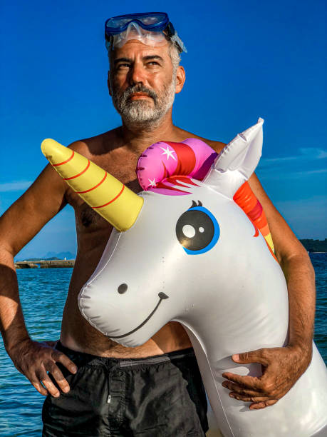 istock Mature Man on Summer Vacations With His Unicorn Inflatable Pool Raft 1157568420