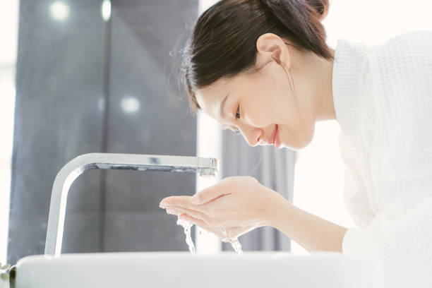 jonge aziatische wwoman wassen haar gezicht - gezicht wassen stockfoto's en -beelden