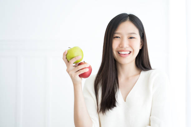 молодая азиатская женщина укусить зеленое яблоко показать сильные зубы - apple women green eating стоковые фото и изображения