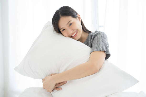Portrait Asian woman and pillow wake up on bed at home stock photo