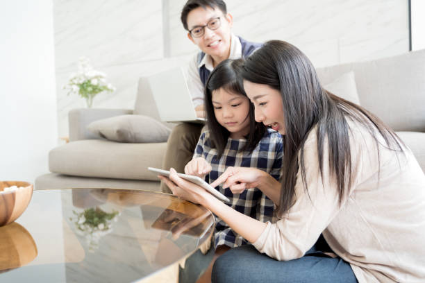 happy asian family spending time together in living room. family and home concept - father digital tablet asian ethnicity daughter imagens e fotografias de stock