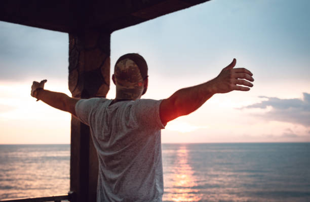 istock Open hands man looking the view of sunset with hat 1157579153