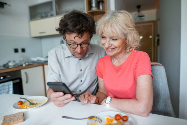 istock Senior couple eating breakfast together and using smart phone 1157580267