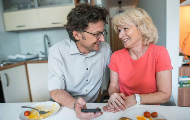 istock Senior couple eating breakfast together and using smart phone 1157580341