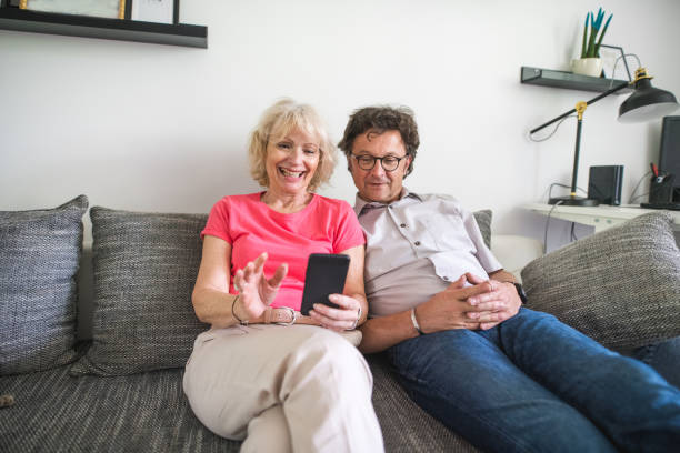 istock Senior couple sitting on the sofa and cuddling and using a smart phone 1157580446