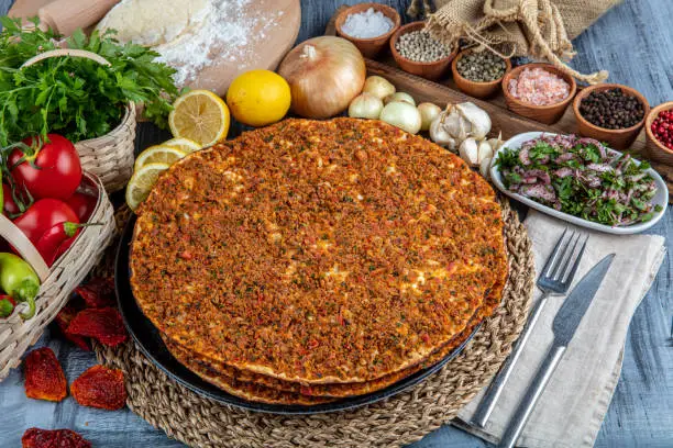 Traditional Turkish Cuisine: Lahmacun turkish delicious pizza with minced beef or lamb meat, paprika, tomatoes, cumin spice, on rustic wooden table background.
