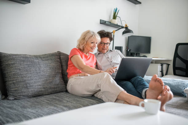 istock Senior couple sitting on the couch and using a laptop 1157582702
