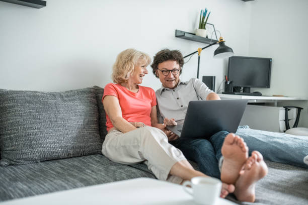 istock Senior couple sitting on the couch and using a laptop 1157582853