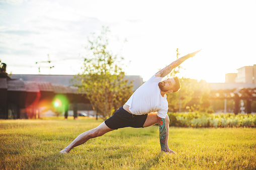 Tattooed man practicing yoga outdoors
