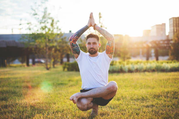 istock Tattooed man practicing yoga outdoors 1157590611