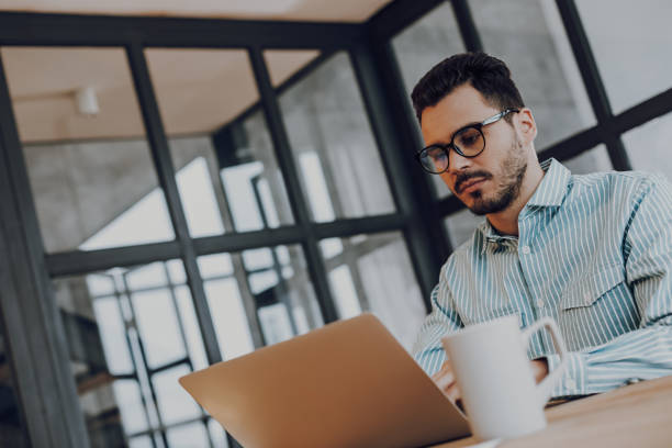 istock Young man in glasses is working on laptop 1157590907