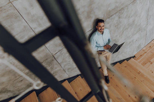 istock Happy man is spending time with laptop at stairwell 1157590911