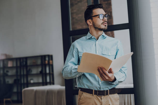 istock Man in glasses with folder working indoors 1157590928