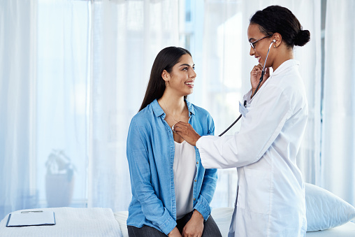 Shot of a young doctor examining her patient with a stethoscope