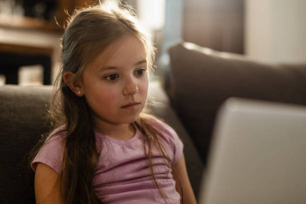istock Pensive little girl using laptop while relaxing at home. 1157604008