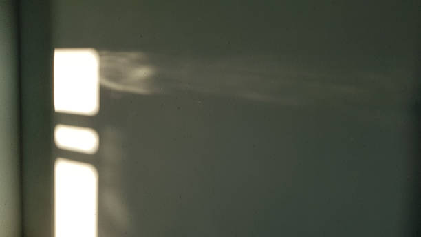 istock Abstract background with white shiny blurred sunbeams look like spotlight in darkness. Bright light rays on grey stucco wall surface. Light and shadow backdrop. 1157617612