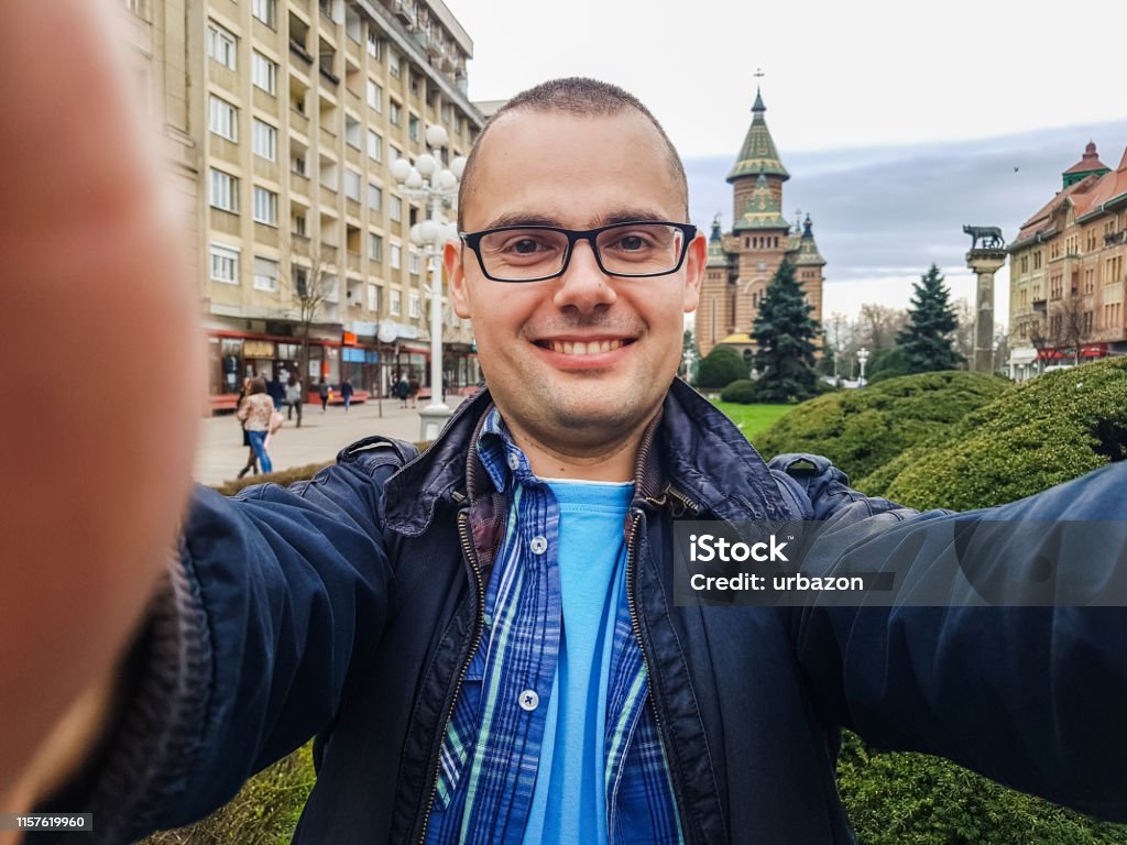 Taking selfie in Timisoara, Romania Young, cheerful, male tourist taking selfie in Timisoara, Romania. Taken on mobile device. Selfie Stock Photo