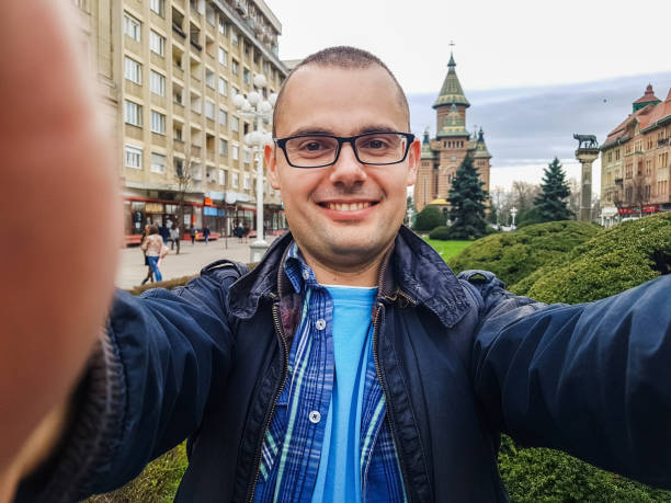 Taking selfie in Timisoara, Romania Young, cheerful, male tourist taking selfie in Timisoara, Romania. Taken on mobile device. taken on mobile device photos stock pictures, royalty-free photos & images
