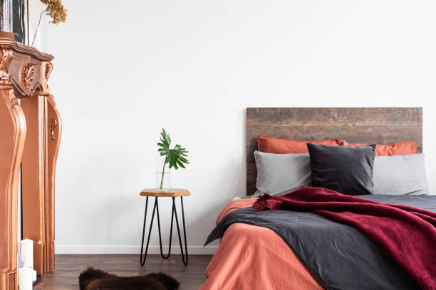istock White interior with wooden bed, grey bedding, bedside table and coppery fireplace 1157620736