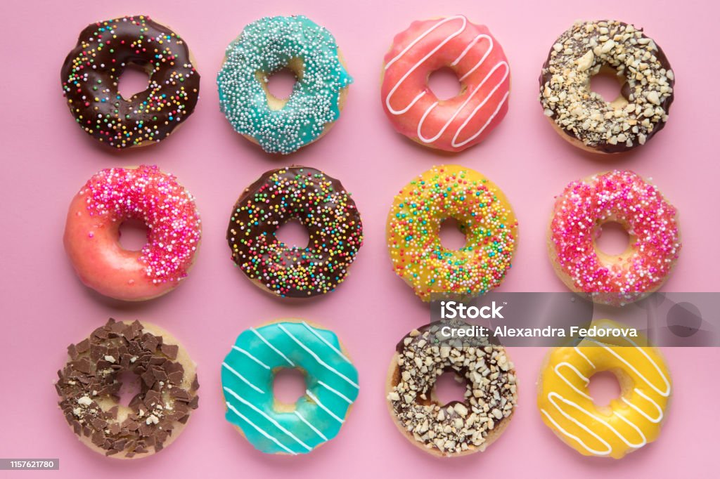 Colorido fondo dulce. Deliciosas rosquillas acristaladas sobre fondo rosa. - Foto de stock de Buñuelo en forma de rosca libre de derechos