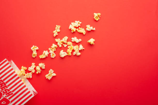 istock Popcorn packaging on a bright red background. sprinkled popcorn. rest and entertainment. Flat lay 1157626778