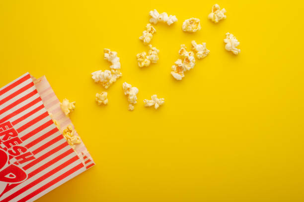 istock packaging with popcorn on a bright yellow background. sprinkled popcorn. rest and entertainment. Flat lay 1157628907