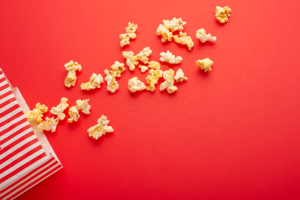 istock Popcorn packaging on a bright red background. sprinkled popcorn. rest and entertainment. Flat lay 1157629062
