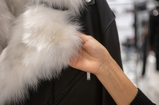 Unrecognizable woman shopping for fur coat