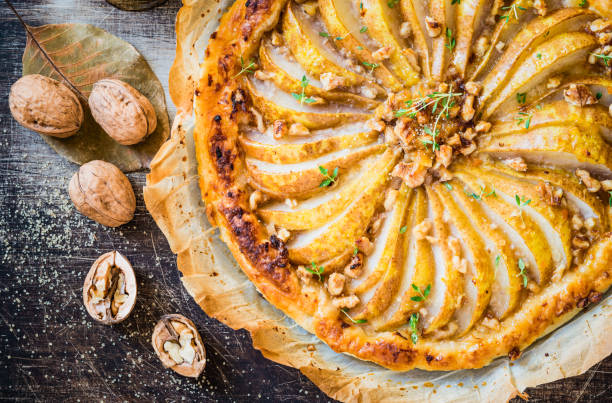 Pear tart with nuts and honey homemade pie on rustic dark background.