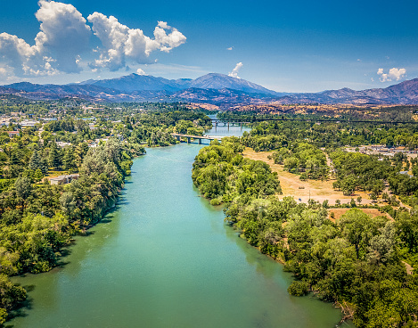An aerial view of the Sacramento River in Redding California. Beautiful blue sky and sparkling aqua water with small bridges crossing the river in the distance.