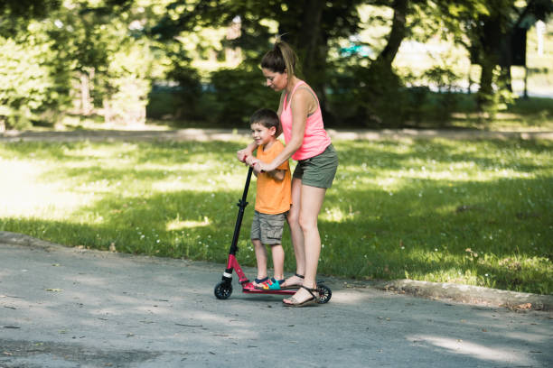 istock Little boy riding a push scooter with his mom 1157660246