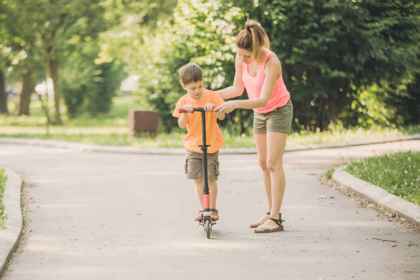 istock Little boy riding a push scooter with his mom 1157660990
