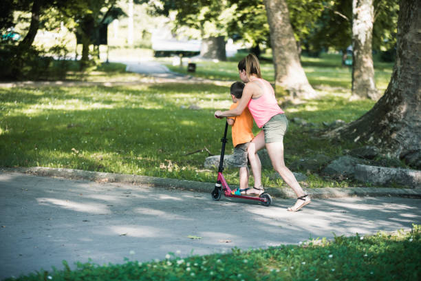 istock Little boy riding a push scooter with his mom 1157661005