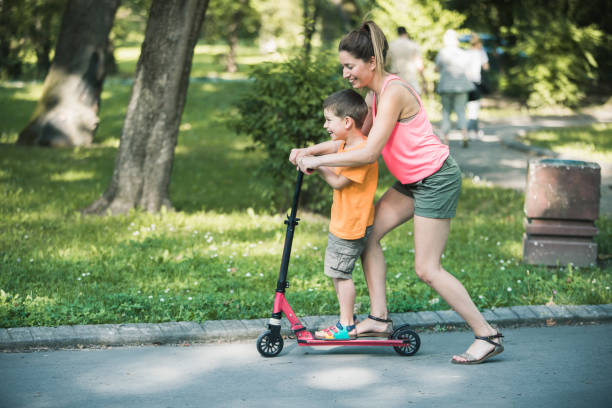 istock Little boy riding a push scooter with his mom 1157661176