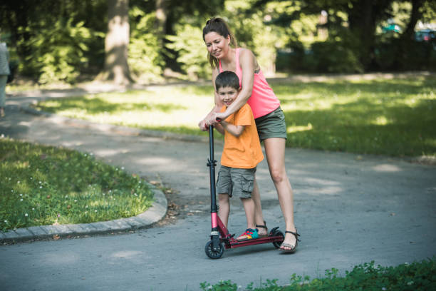 istock Little boy riding a push scooter with his mom 1157661203