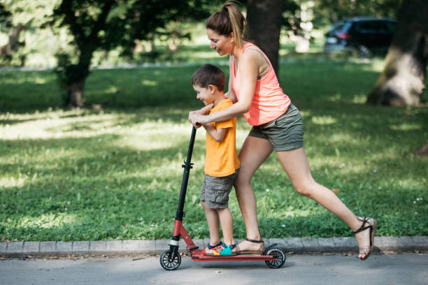 istock Little boy riding a push scooter with his mom 1157661212