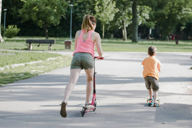 istock Little boy riding a push scooter with his mom 1157661956
