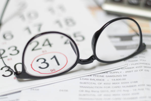 glasses on credit card statement and calendar highlight on last day of month as due date and blur calculator - debt national landmark credit card paying imagens e fotografias de stock