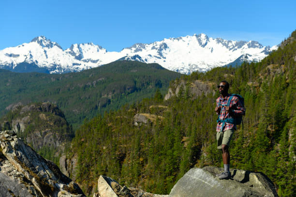 Female hiker standing on rocky trail with snow-covered mountains in background