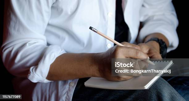 Cropped Shot Of Man Writing On Paper Notebook With Pencil Stock Photo - Download Image Now