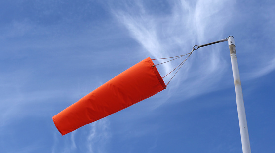 Bright orange wind sock on a strong breeze showing wind direction